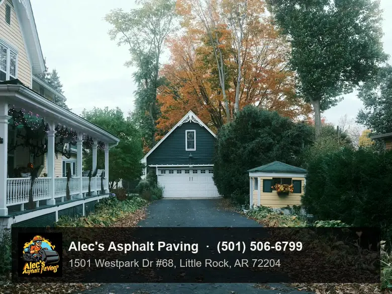 A long dark asphalt driveway running past a porch to a detached garage in autumn