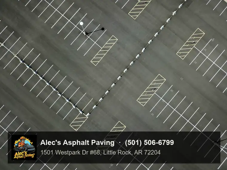 A parking lot seen from directly above, crisp white stall lines and hatched islands