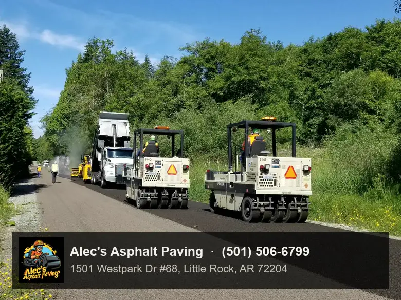 Two rubber-tired rollers working a freshly surfaced lane behind a truck on a tree-lined road