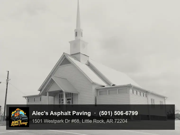 A small country church with a tall steeple and an accessible ramp, behind an asphalt parking lot with crisp stall lines