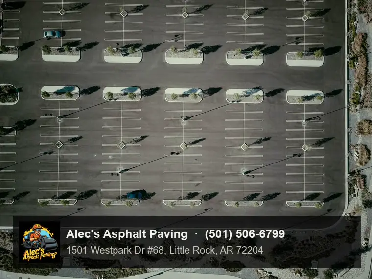 A drone view straight down on a large, nearly empty commercial parking lot with double stall lines, light poles, and planted islands