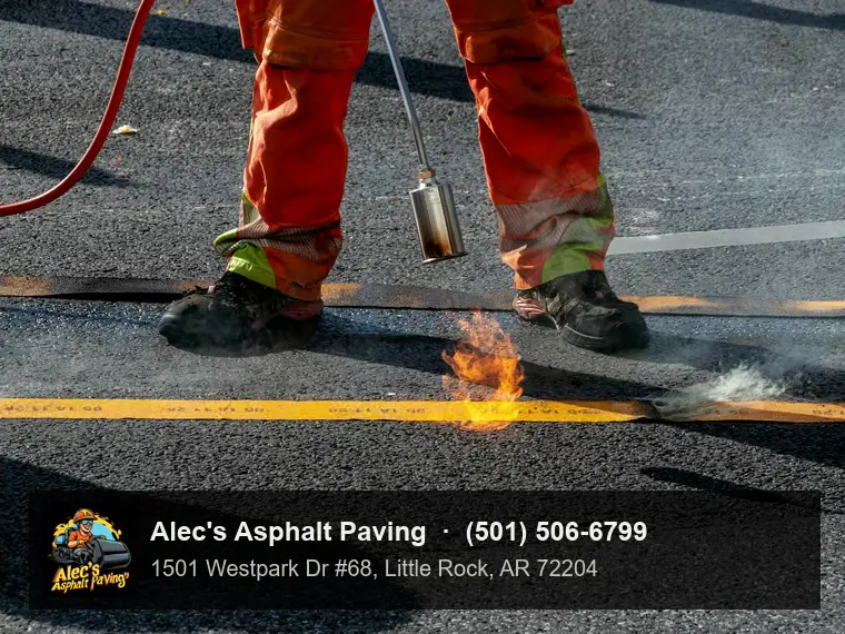 A worker heating a thermoplastic road marking into the asphalt with a torch
