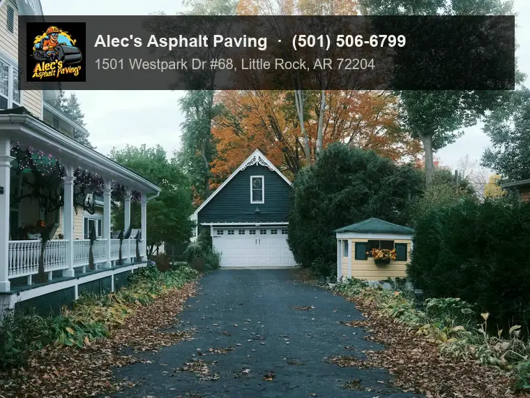 A long asphalt driveway running past a porch to a detached garage in autumn