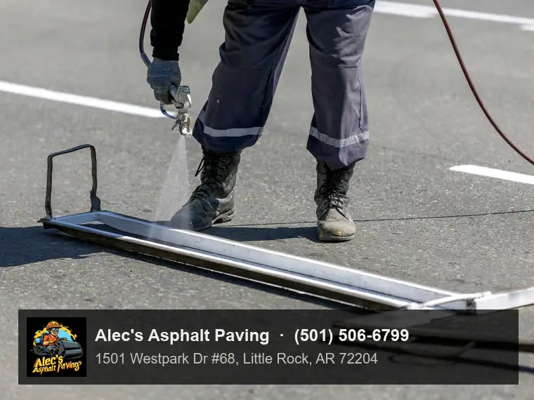 A worker spraying a white stall line along a metal stencil guide