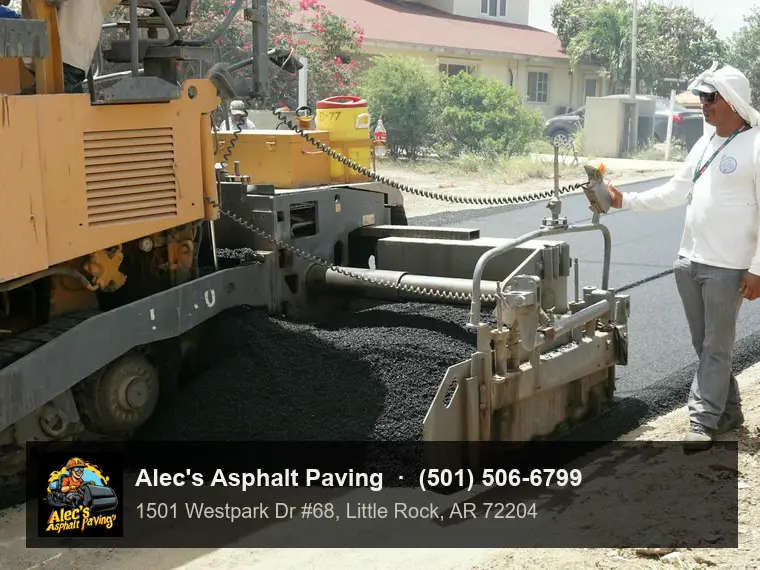 A screed operator walking beside a paver as hot mix spreads across the road