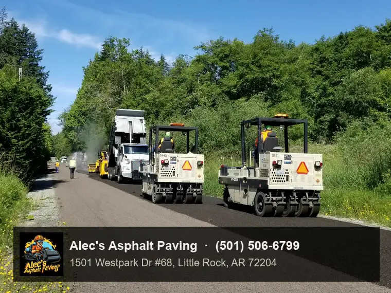 Two rubber-tired rollers following a truck along a freshly surfaced rural road