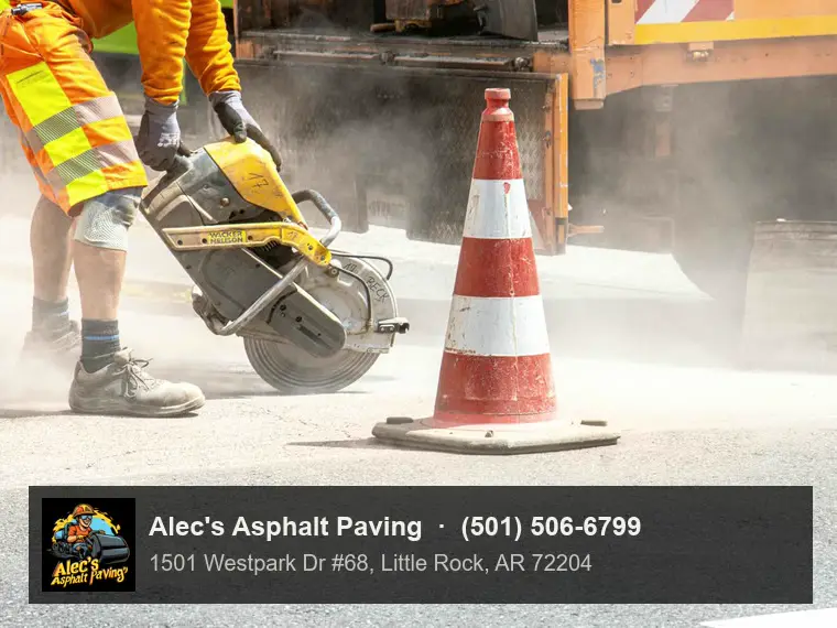 A worker in hi-vis cutting through asphalt with a cut-off saw beside a traffic cone, dust rising, a work truck behind