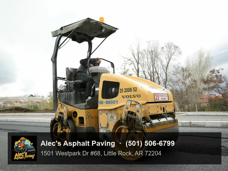 A tandem steel-drum roller compacting fresh hot-mix asphalt, operator in the seat