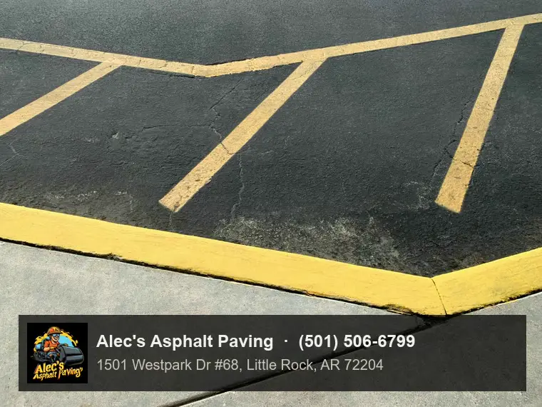 Hatched striping on a parking lot meeting a painted curb beside a concrete sidewalk